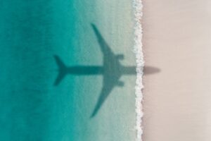 Shadow of an aeroplane flying over a tropical shoreline.