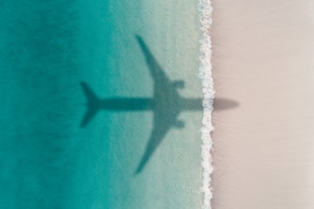 Shadow of an aeroplane flying over a tropical shoreline.