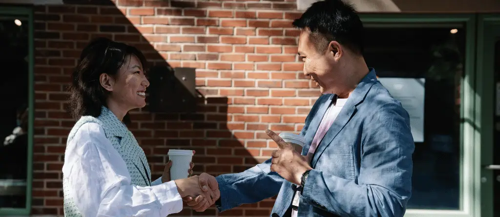a male meeting his female colleague for coffee, shaking hands.