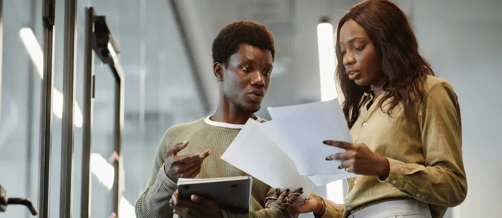 A woman showing her male colleague some papers with reports on them in an office.
